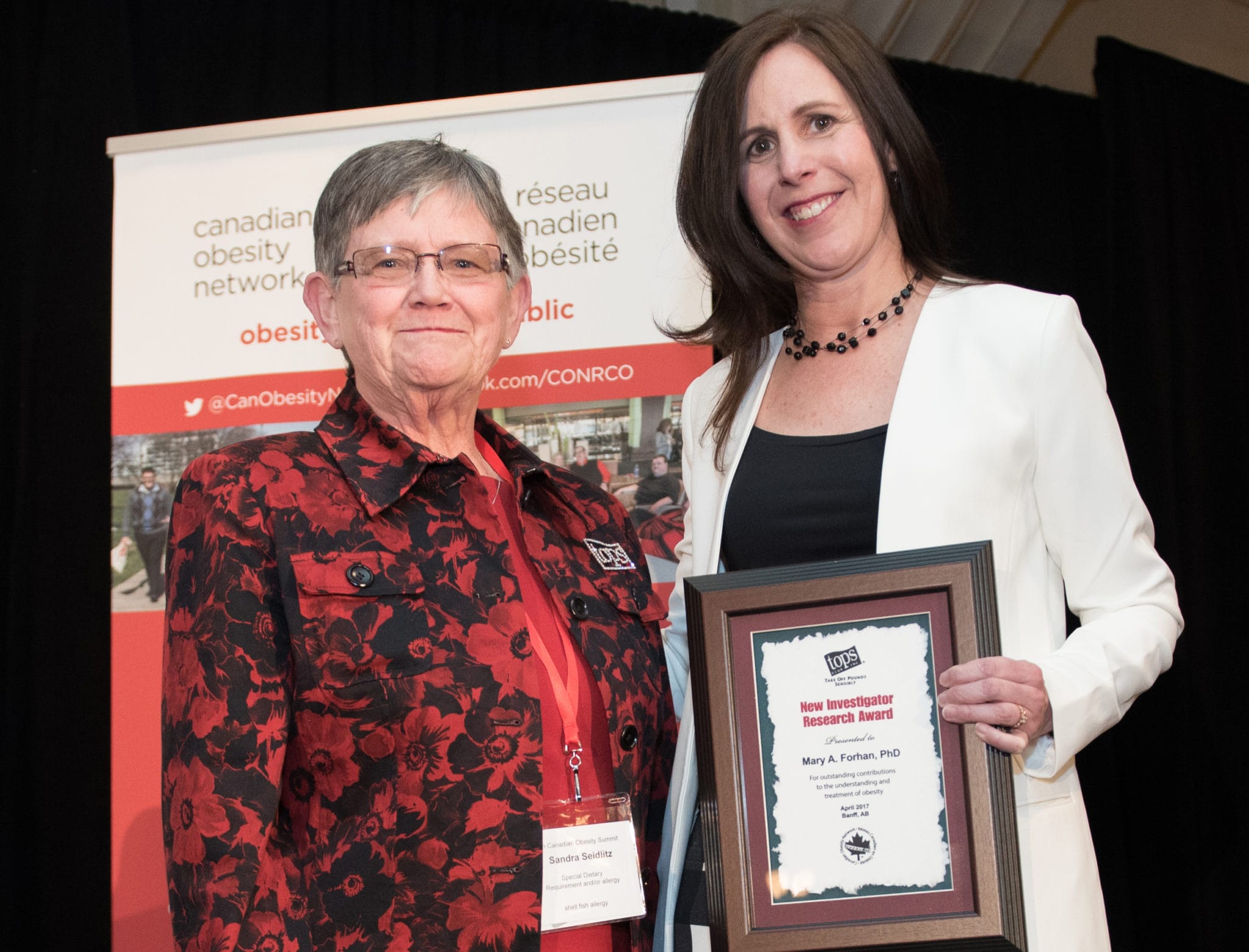 Two women posing with an award certificate at a canadian obesity network event.