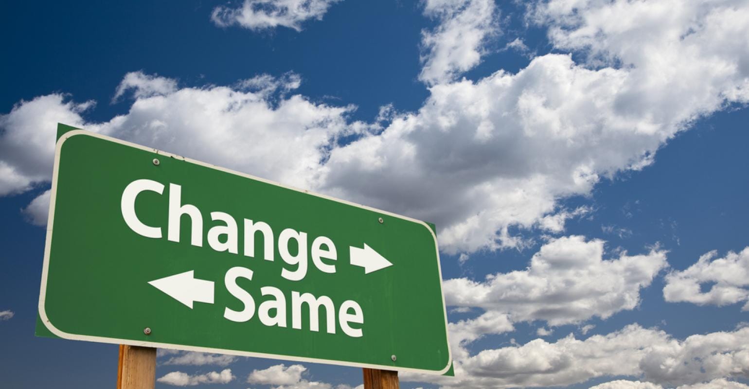 Road sign with arrows and text "change" pointing left and "same" pointing right under a cloudy blue sky.