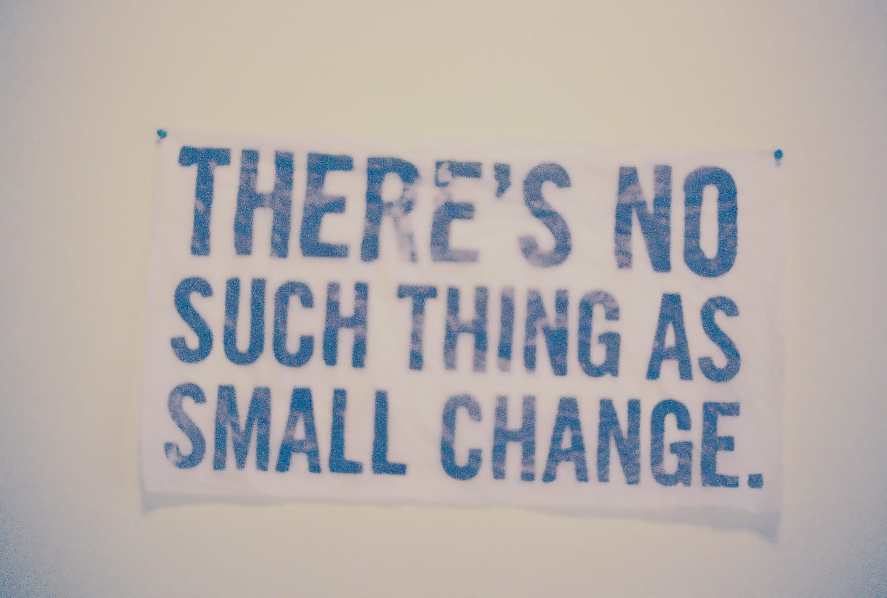 A banner with the phrase "there's no such thing as small change" in blue letters on a white background, slightly out of focus.