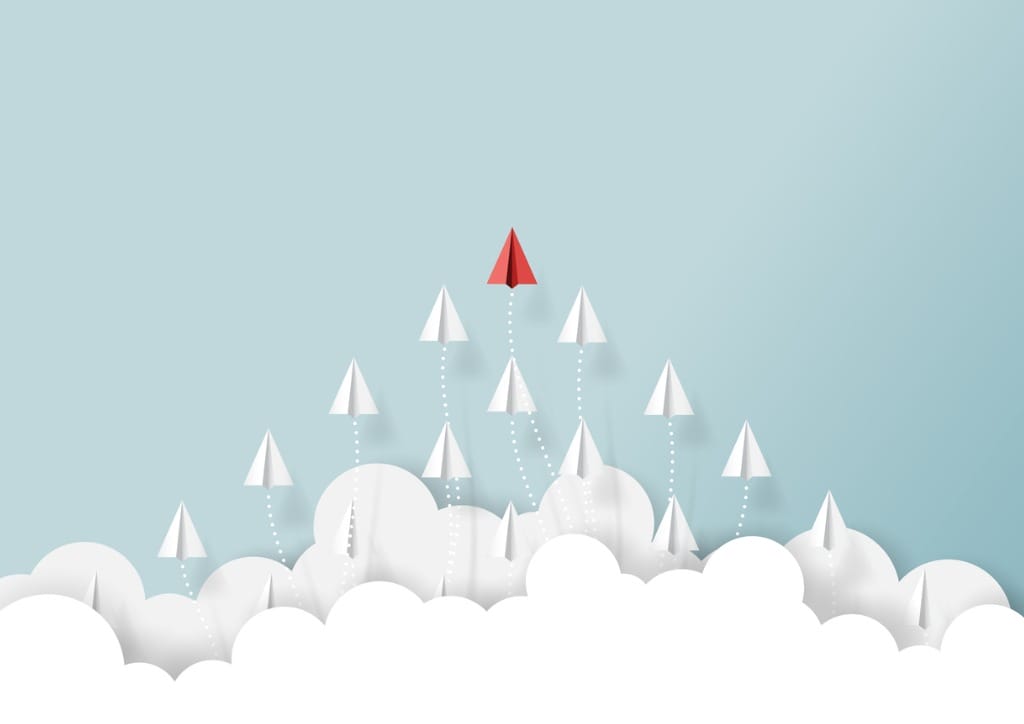 A graphic showing a red paper airplane flying above a group of white paper airplanes against a light blue background with clouds.