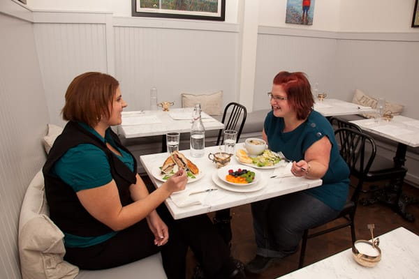 Two women dining in a restaurant, enjoying a meal and conversation at a table set with plates of food.