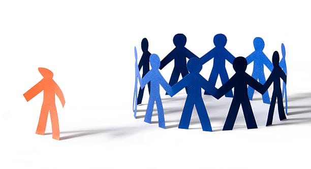 A circle of blue paper cut-out figures holding hands, with an orange cut-out figure standing apart from the group.