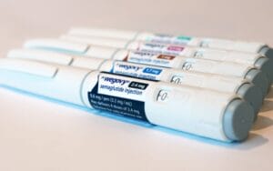 Rangée de stylos d'injection de médicaments contre le diabète avec des étiquettes sur une surface blanche.